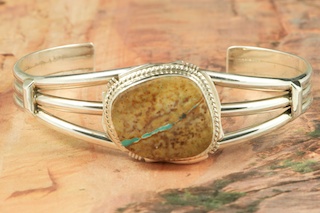 Genuine Boulder Turquoise set in Sterling Silver Bracelet. The cabochon is Boulder Turquoise, you can see the veins of Turquoise running through the host rock. The Boulder Turquoise Mine is located in northeast Nevada. It was discovered in 1970 by a Shoshone sheep herder. Production is small due to the remote location and winter weather. Boulder Turquoise is valued for both it's beauty and rarity. Every stone is unique. Created by Navajo Artist Kathy Yazzie. Signed.